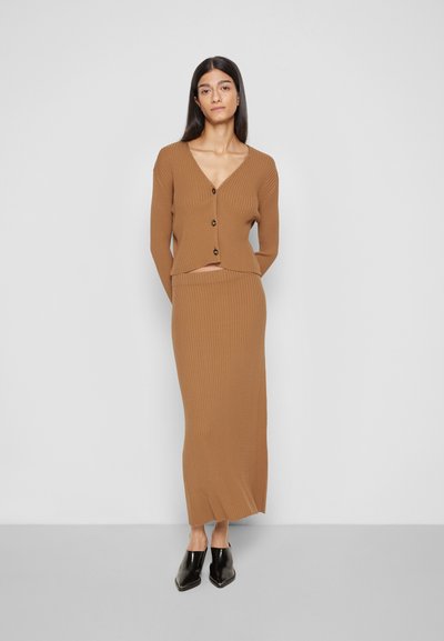 Conjunto em dois peças em malha canelada castanha, apresentando um cardigã cropped com botões e uma saia maxi ajustada. Textura suave e design ajustado ao corpo.