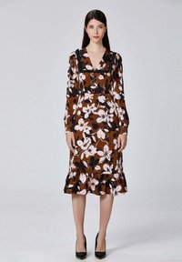 Robe florale marron avec des manches longues, décolleté en V, volants noirs au col, taille accentuée et ourlet volanté, ornée de fleurs roses et noires.