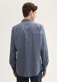 Herren Langarmhemd in Dunkelblau, aus weichem Textil mit subtilen Mustern, mit Knopfmanschetten und einem klassischen Kragen, mit geradem Rückenteil.