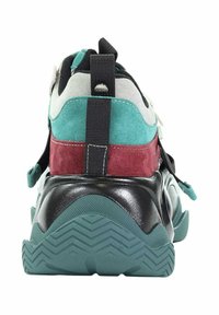 Masywne sneakersy z czarną podeszwą, panelami w odcieniach teal i burgundowych z zamszu, białymi akcentami oraz czarną pętlą do ciągnięcia, widoczne z tyłu na białym tle.