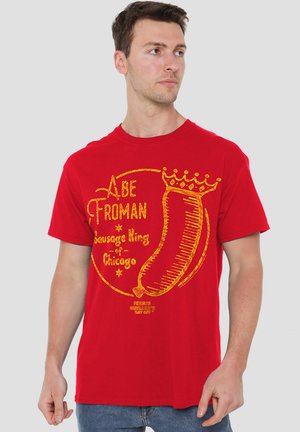 Red cotton t-shirt featuring yellow graphic text and a sausage illustration, with the words "Abe Froman, Sausage King of Chicago" and a crown design.