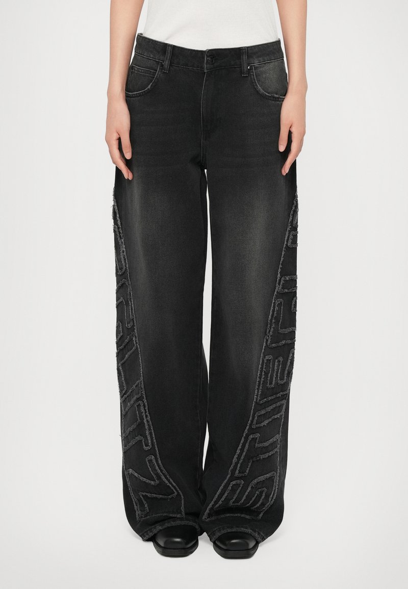 Black denim wide-leg pants featuring frayed side seams and embroidered accents. Front pockets and a classic five-pocket design.