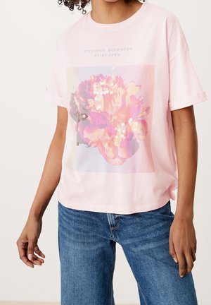 T-shirt en coton rose avec une coupe décontractée, arborant un motif floral orné de sequins, et du texte au-dessus du design en bleu clair.