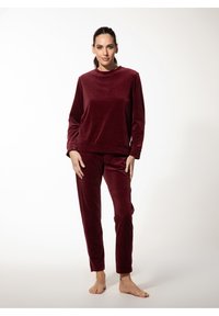 Bordeaux kleurig, plush lounge-outfit bestaande uit een long-sleeve T-shirt met ronde hals en taps toelopende broeken. Zachte textuur met aansluitende manchetten en tailleband.