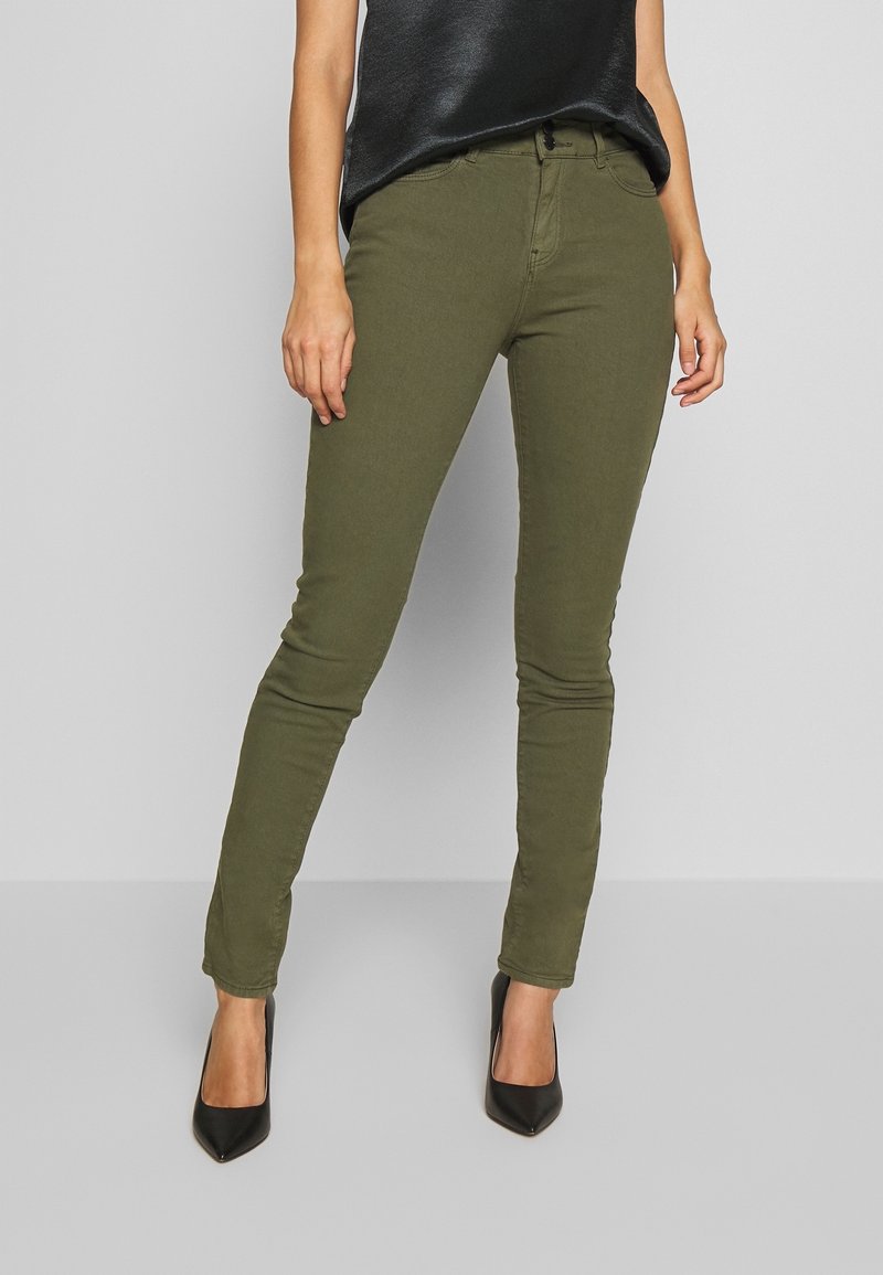 Jean skinny vert olive, en coton extensible, avec un design classique à cinq poches et une finition lisse et texturée.