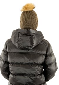 Giacca a vento nera con finitura lucida, dotata di cappuccio e design a righe orizzontali. Gli accessori includono un berretto lavorato a maglia color khaki con pompon beige.