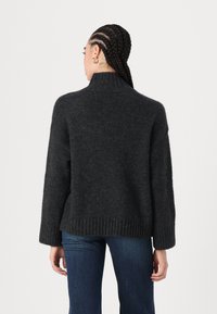 Pulover tricotat de culoare gri închis, cu guler înalt, tiv ondulat și mâneci lungi, fabricat dintr-un material texturat moale.
