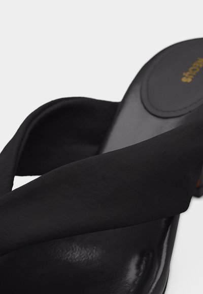 Čierna otvorená obuv bez šnurovania s širokým látkovým remienkom cez nôhu a nízkym blokovým opätkom.