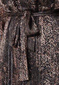 Tissu imprimé léopard dans des nuances de marron et de noir, avec une ceinture à nouer à la taille, des rayures verticales subtiles et une texture douce.