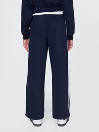 Navy blue wide-leg sweatpants in soft fabric, featuring a white side stripe. Elastic waistband, smooth texture, and relaxed fit.