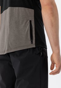 Top à manches courtes avec un design en blocs de couleurs noir et gris, doté d'une poche zippée sur le côté. Fabriqué en tissu doux et léger.