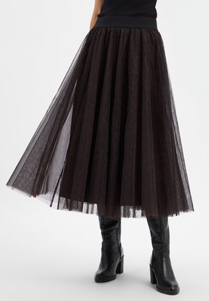 Black layered tulle midi skirt worn with black heeled knee-high boots on a white background.