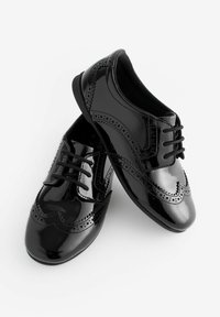 Zwarte gepatineerde leren schoenen met veters, brogue-details, ronde neus en een gladde textuur, die een klassieke oxfordstijl tonen.