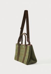 Πράσινη και καφέ καρό τσάντα από ύφασμα με διπλές λαβές και ρυθμιζόμενο μακρύ λουρί ώμου σε λευκό φόντο.