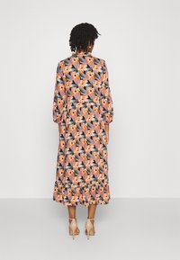 Robe longue à fleurs avec des fleurs vibrantes orange et blanches sur fond bleu, présentant des manches bouffantes et un ourlet volanté.