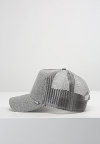 Casquette grise avec un devant en tissu solide et un dos en maille. Elle présente une visière incurvée et une étiquette sur le côté. Matériau texturé et design respirant.