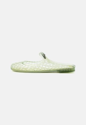 Chaussure en plastique transparent à enfiler avec motif en treillis et bride réglable à boucle sur fond blanc.