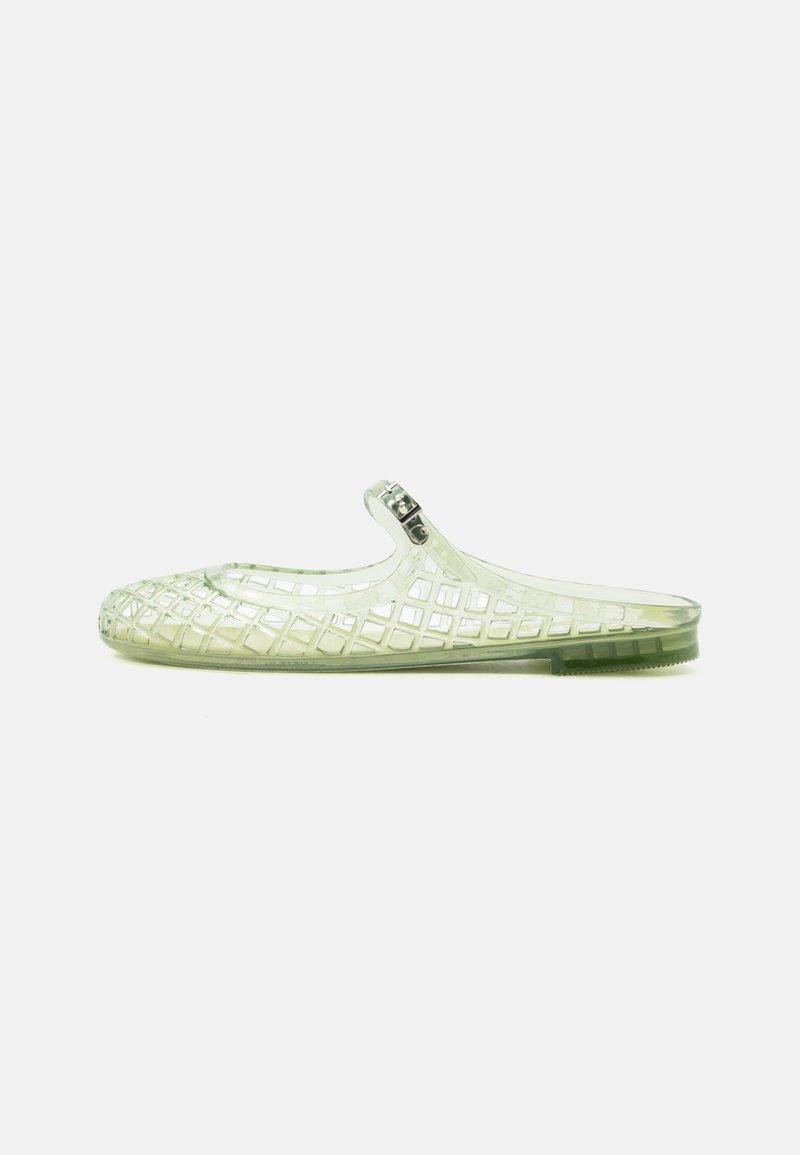 Διαφανές πλαστικό παπούτσι τύπου slip-on με δικτυωτό σχέδιο και ρυθμιζόμενο λουράκι με αγκράφα σε λευκό φόντο.