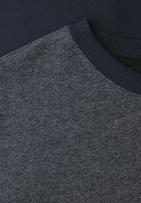 Close-up van een donkergrijze gebreide trui met een marineblauwe geribbelde boothals.