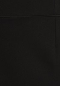 Tissu noir avec une couture horizontale dans la section supérieure et une couture verticale sur le côté droit.