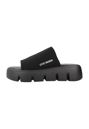 Chanclas negras con parte superior de tela acanalada y tira ancha. Presentan una suela de goma gruesa y texturizada con surcos profundos. Logotipo de la marca presente.