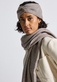 Écharpe et bandeau en kaki fabriqués en tissu texturé doux, avec un design tressé sur le bandeau et un style drapé sur l'écharpe.