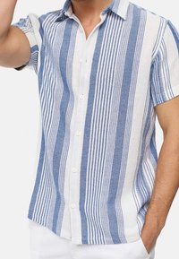 Camisa de botones de manga corta en un patrón de rayas azul y blanco, con una textura tejida y un collar clásico, con botones blancos.