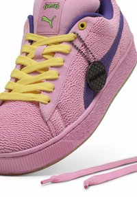 Roze sneaker van textiel met een structuur, paarse accenten en gele veters. Voorzien van een metalen label en een rubberen zool. Inclusief een extra veter.