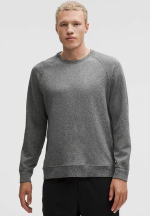 Grå tekstureret sweatshirt med lange ærmer, ribbet design, rund hals og en afslappet pasform, der har en lige kant og raglanærmer.