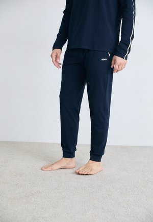 Navy Blaues Langarmshirt und passende Jogginghose aus weichem Stoff. Das Shirt hat kontrastierende Seitenstreifen; die Jogginghose trägt ein Logo auf der Hüfte.