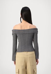 Off-the-shoulder, fitted gray ribbed top with long sleeves, textured material, and pleated neckline detail, paired with beige cargo pants.