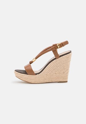 Sandale compensée en cuir marron avec un talon en jute tressé, bride de cheville réglable et accents en métal doré. Dotée d'une semelle intérieure douce et rembourrée.