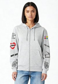 Felpa grigia con zip e coulisse, decorata con vari disegni grafici in nero e rosso sulle maniche, e con emoji colorate sulla spalla destra.