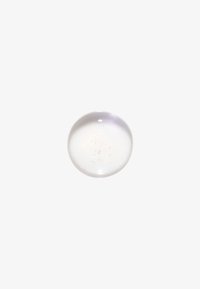 Goutte de gel claire et ronde avec de petites bulles d’air à l’intérieur sur fond blanc uni, mettant en valeur une texture lisse et translucide.