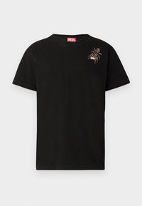 T-shirt en coton noir à manches courtes, présentant un motif de spider décoratif sur le côté gauche de la poitrine et une étiquette rouge du logo Diesel au niveau du col.