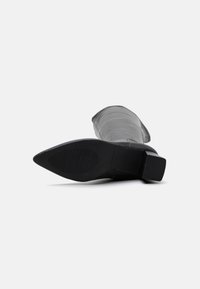 Black leather ankle boot with a rounded toe, textured sole, and block heel. The shaft is smooth with a slight sheen.