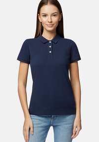 Granatowa koszulka polo wykonana z bawełny, z klasycznym kołnierzykiem, krótkimi rękawami oraz zapięciem na trzy guziki. Gładka, płaska tekstura.