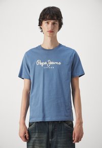Mėlyna medvilnė T-palaidinė su apvaliu iškirpimu ir trumpomis rankovėmis. Priekyje yra balta siuvinėta užrašas "Pepe Jeans LONDON".