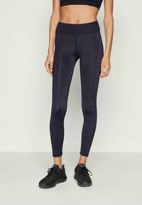 Leggings pretos de cintura alta feitos de um tecido liso e elástico, com um silhueta ajustada, leves e sem padrões ou detalhes visíveis.