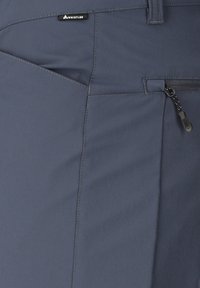 Harmaa kangas, jossa on viistottu sauma, vetoketjullinen tasku vetimen kanssa ja Whistlerin merkkilappu vyötärövyön lenkissä.