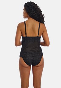 Black lace tankini with adjustable straps, featuring a geometric pattern and matching brief. Soft texture and fitted design highlight the body.