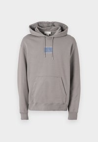 Sivá mikina s kapucňou vyrobená z mäkkej tkaniny, s nastaviteľnými šnúrkami, "kangaroo" vreckom a logom na hrudi v modrej a bielej farbe. Má ribbované manžety a lem.