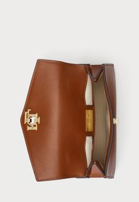 Läderplånbok i tan med guldfärgad hårdvara, strukturerad design och fodrad insida. Har ett öppet tryckknäppslås och en logotyp inuti.