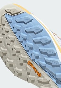 Zool van een schoen met beige en blauwe robuuste profielpatronen en een oranje Continental-logo voor verbeterde grip en duurzaamheid.