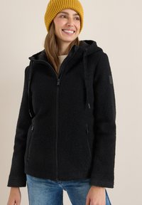 Veste en polaire noire avec une capuche, fermeture éclair et deux poches latérales. Présente un tissu texturé et des sangles contrastées sur la capuche.