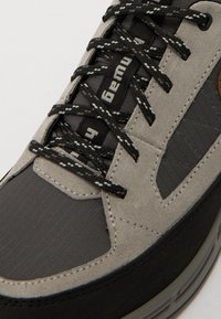 Szürke és fekete sneaker, amely velúr és textil anyagokból készült, textúrázott részletekkel, lapos fekete cipőfűzőkkel és látható légpárnás gumitalppal.