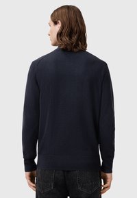 Marinefarbener Strickpullover mit langen Ärmeln, einem runden Halsausschnitt und gerippten Bündchen. Glatte Textur mit dezenten Schulterdetails.