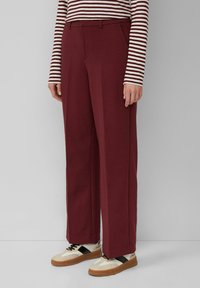 Bordeaux wijde broek gemaakt van zachte stof, met een klassieke pasvorm en zijzakken, gecombineerd met beige en zwarte sneakers.