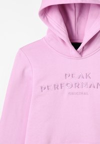 Sudadera rosa claro con capucha frontal y texto bordado "PEAK PERFORMANCE ORIGINAL" en el pecho.