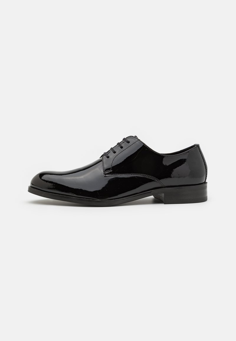 Zapato de vestir de charol negro con un acabado suave, puntera redondeada, cordones tradicionales y un tacón bajo.